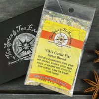 A packet of Vik's Garlic Fix Spice Blend - Barter Box sits on a black branded box with dried star anise nearby. This versatile garlic blend is perfect for enhancing dishes or including in a gift sampler.