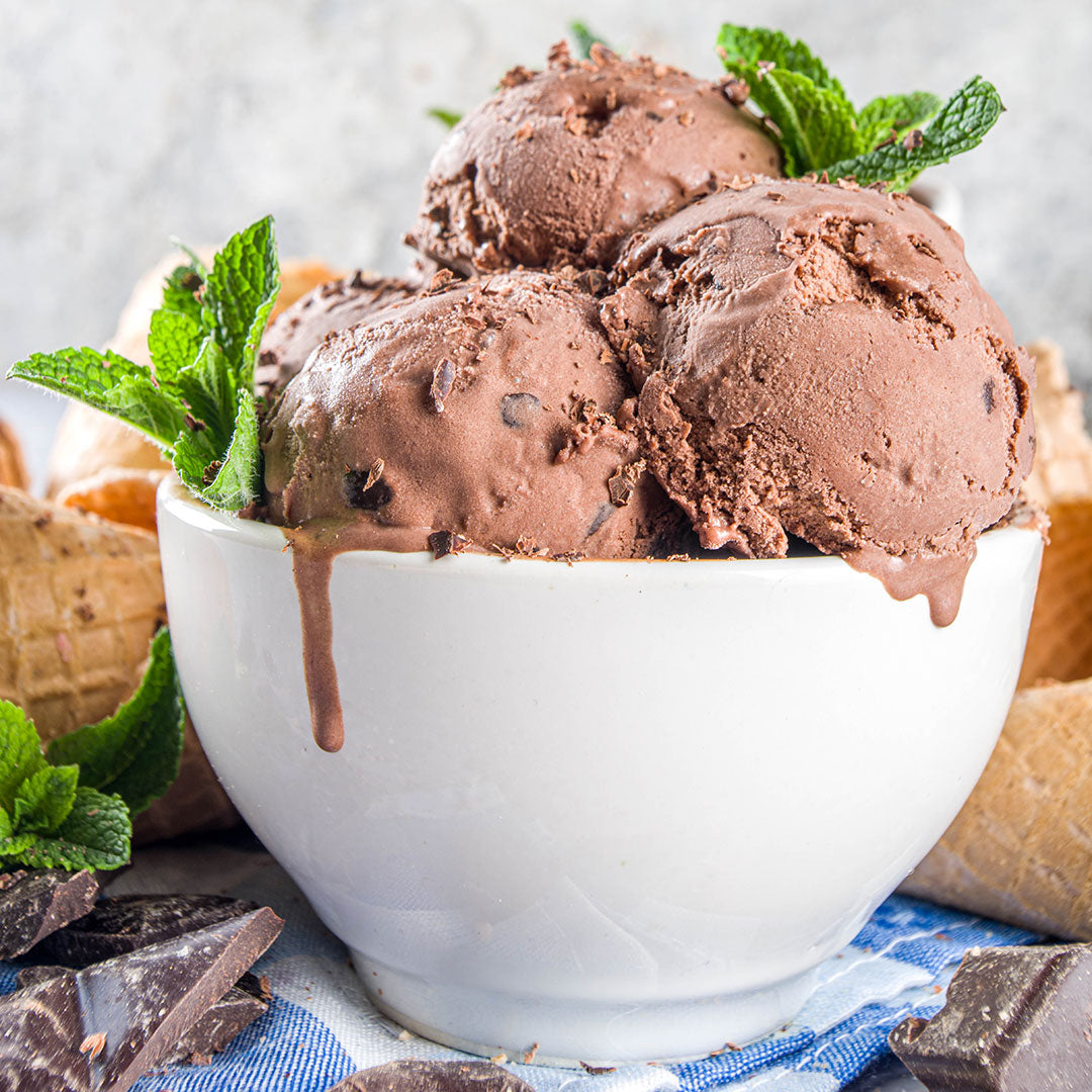 Bowl of chocolate ice cream with mint leaves on a light background