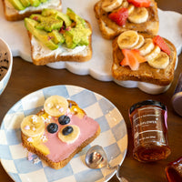 Wildflower Honey Jar next to toast with peanut butter or yogurt and various fruits