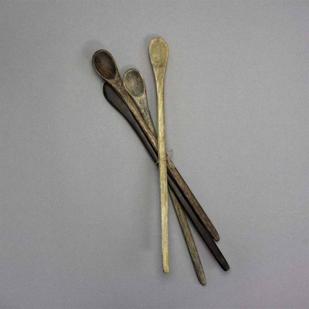 Four Wooden Tasting Spoons in assorted brown shades are fanned out on a plain gray background, highlighting their rustic charm. These essential kitchen tools combine a well-used look with varied natural tones.