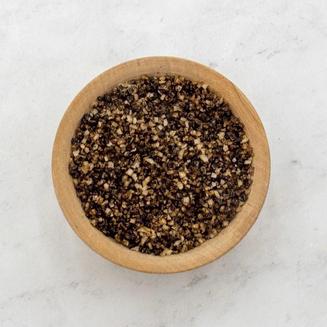 A small wooden bowl filled with Porcini Mushroom Sea Salt sits on a light, textured surface.