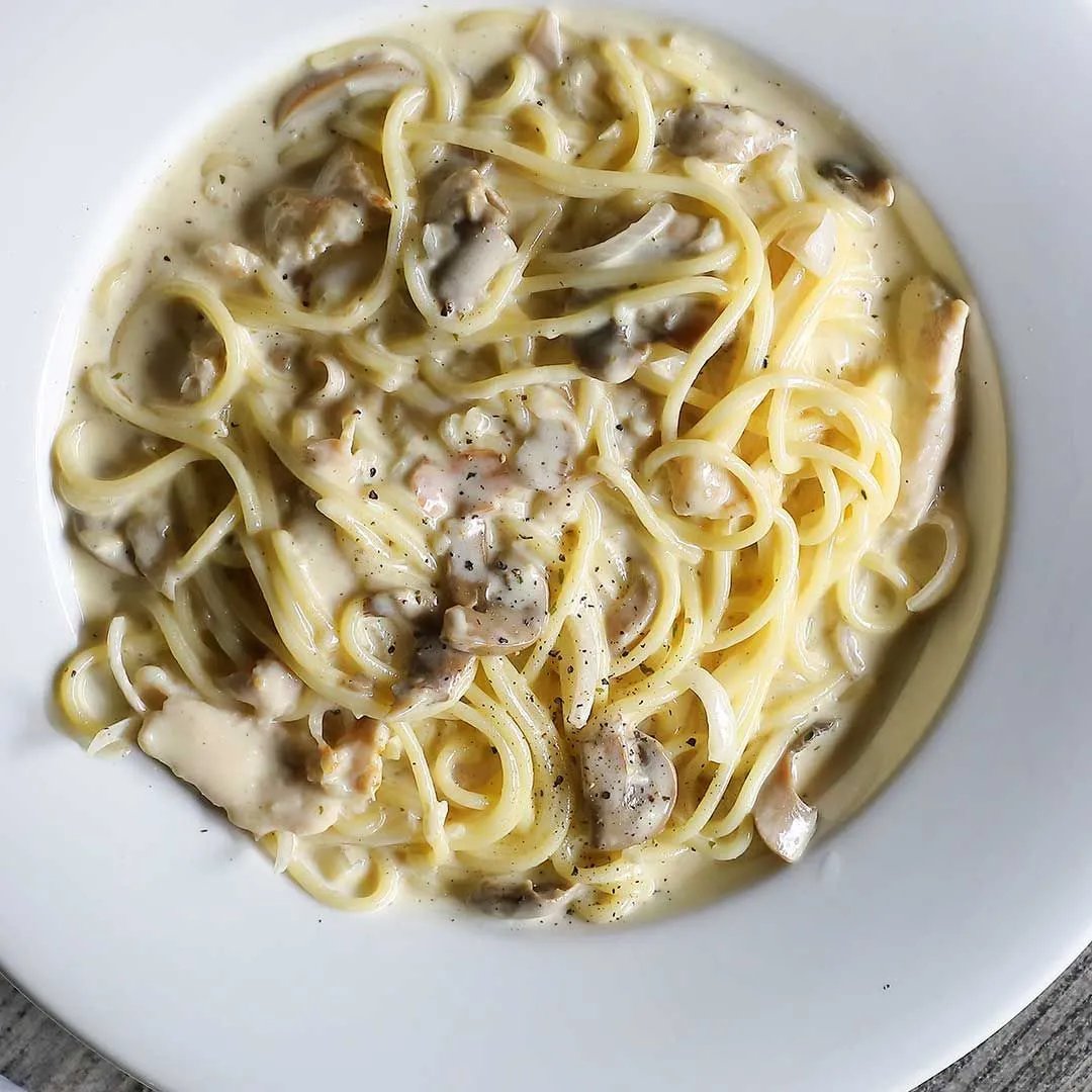 Creamy spaghetti with chicken and mushrooms, finished with a sprinkle of Porcini Mushroom Sea Salt and ground black pepper, served in a white bowl.