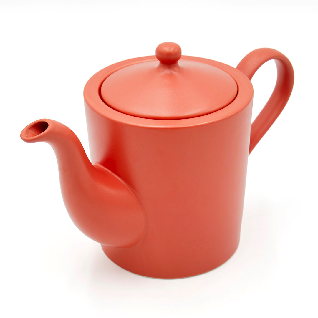 The Cactus Flower Teapot features a matte red ceramic finish with a round body, matching lid, curved spout, and handle—ideal for pairing with your favorite tea mug infuser on any white tabletop.
