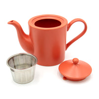 The Cactus Flower Teapot, a red ceramic teapot with handle and spout, is displayed with its lid set aside. Beside it rests a tea mug infuser, ideal for steeping loose leaf blends.