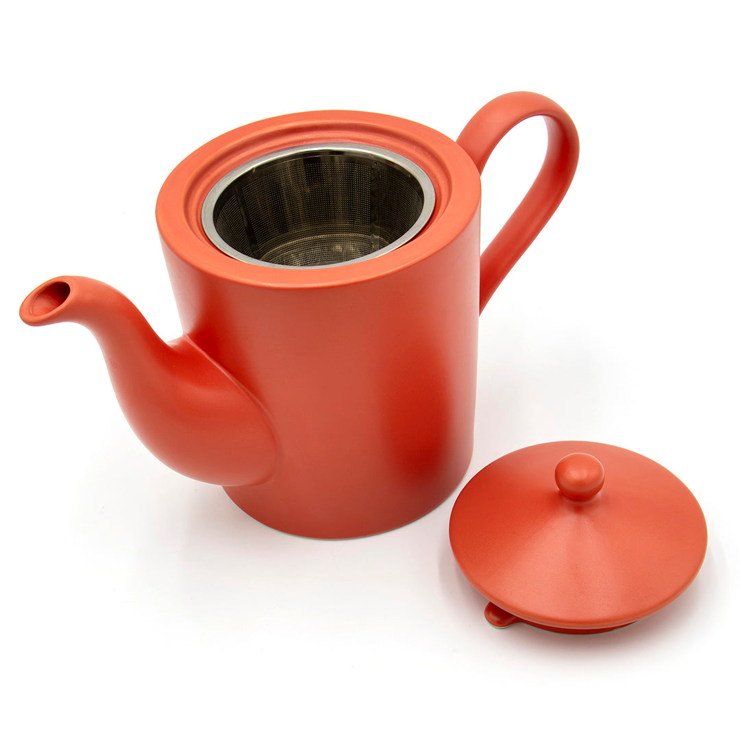 The Cactus Flower Teapot is a red ceramic teapot with a curved spout and handle, shown with its matching lid placed beside it and a stainless steel tea mug infuser visible inside.
